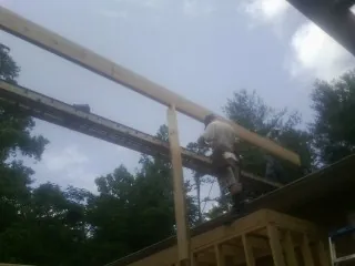 Carpenter setting a ridge beam over a new addition frame — Ice Dam Removal by Roofing Brothers in Seaford