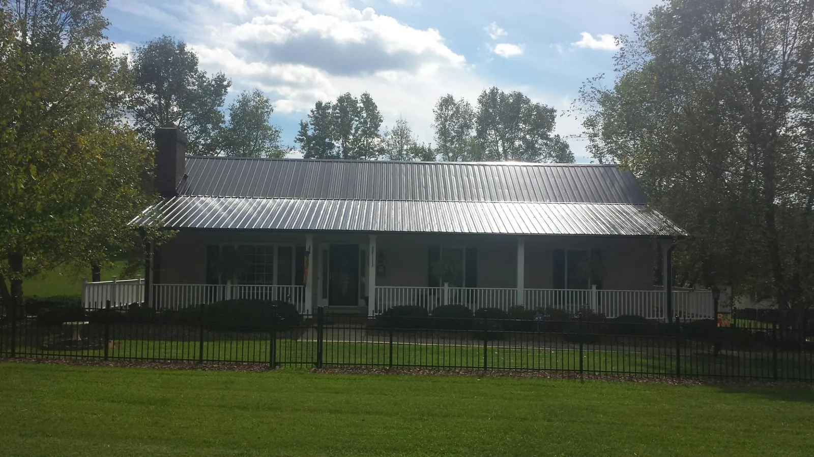 Gray metal roof on a brick ranch with a full width front porch — Gutter Guard Installation work by our crew in Seaford