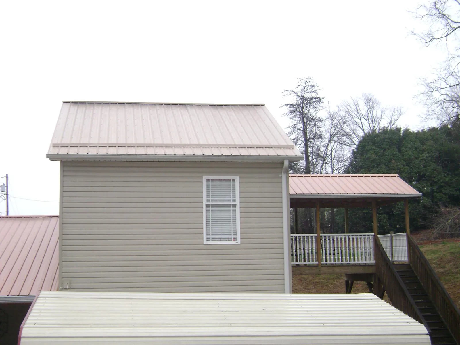 Tan metal roofs on a two story addition and attached porch, from a Roof Replacement job in Seaford